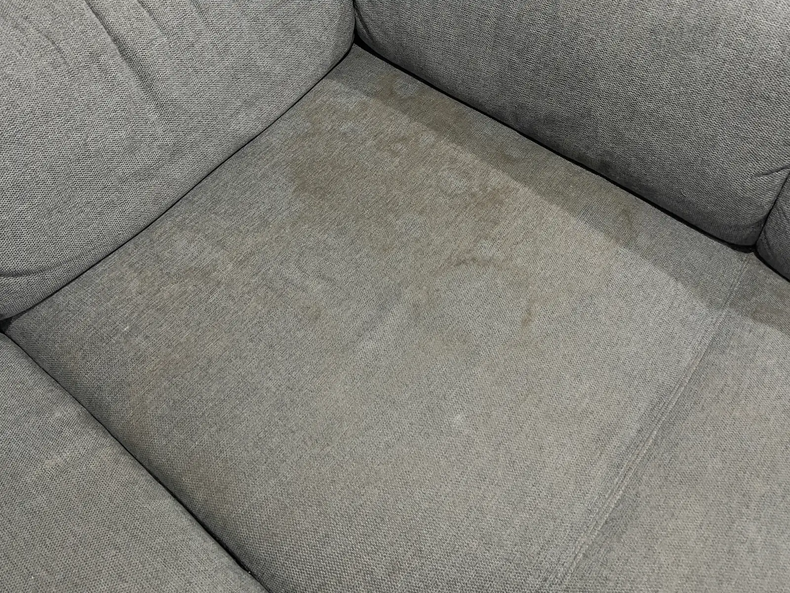 Grey fabric corner lounge with a heavily soiled seat cushion before cleaning, Melbourne’s west