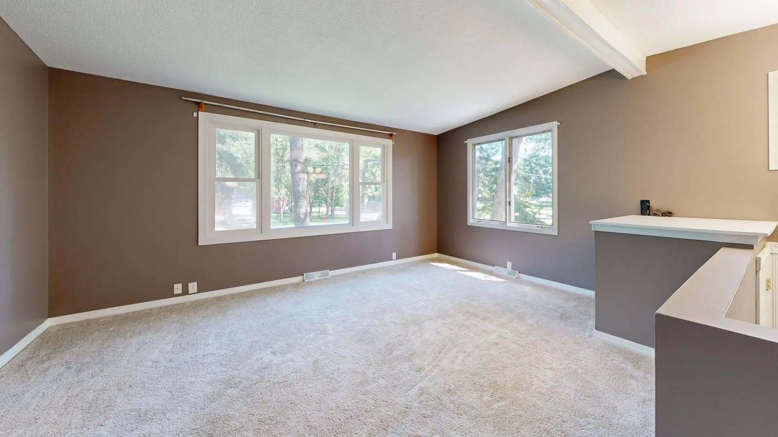 Freshly cleaned pale wall-to-wall carpet in a bright empty lounge room ready for inspection