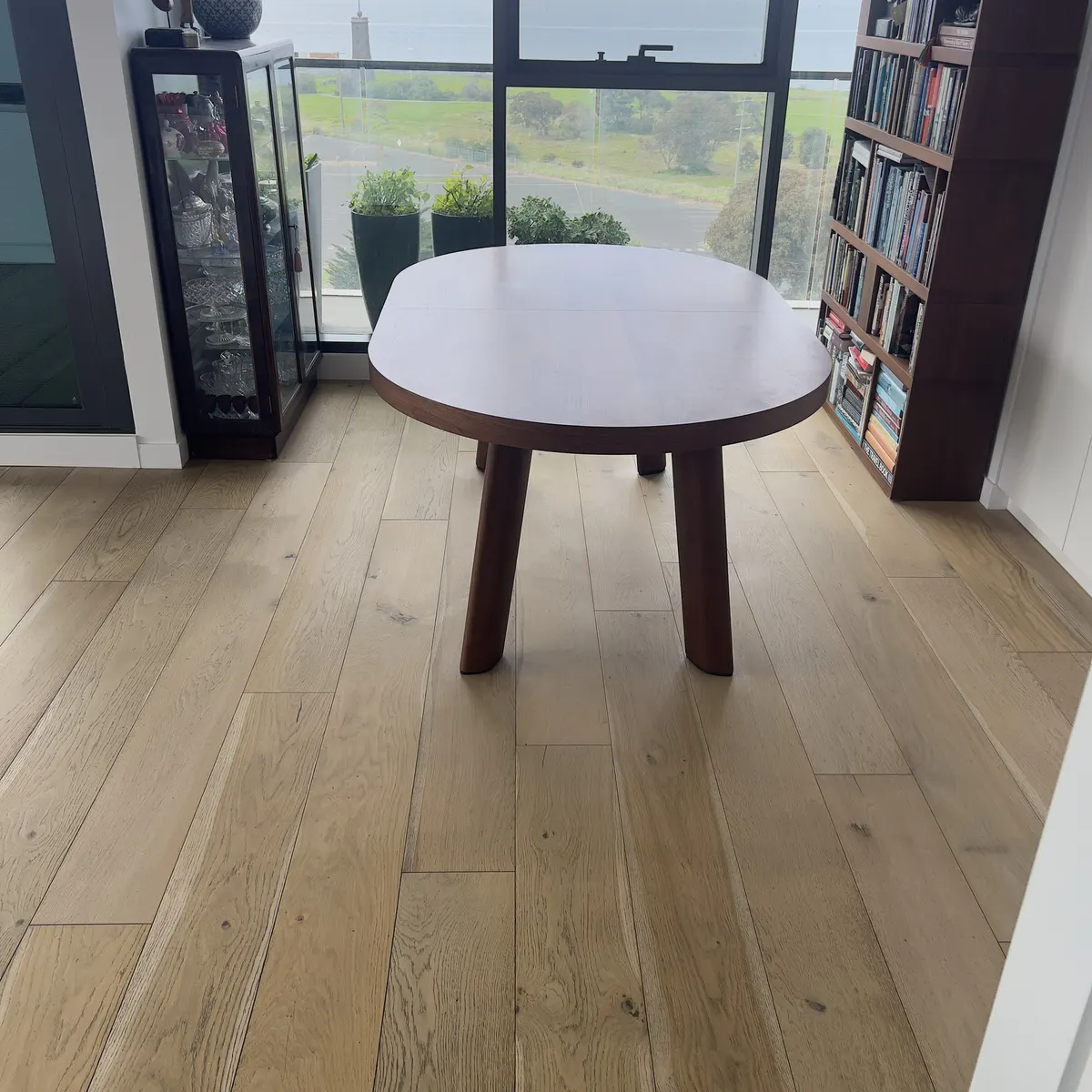 Timber floor around a round table in the same apartment, after cleaning.